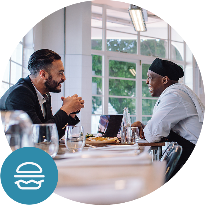 Franchise owner sitting at a table with a chef Franchise owner sitting at a table with a chef