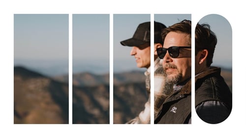 Two employees sitting outside in the Utah mountains looking at the landscape.