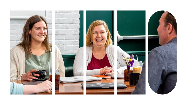 Three employees seated at a table having a conversation.