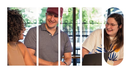 Three employees at a table laughing and drinking coffee.