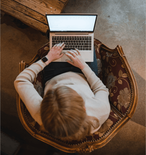 Top-down view of a person sitting on a chair and working on a laptop