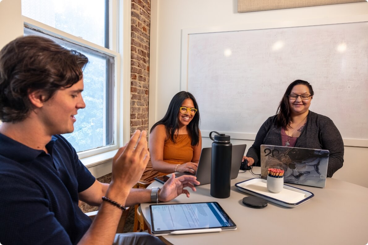 Three employees on their laptops having a meeting.
