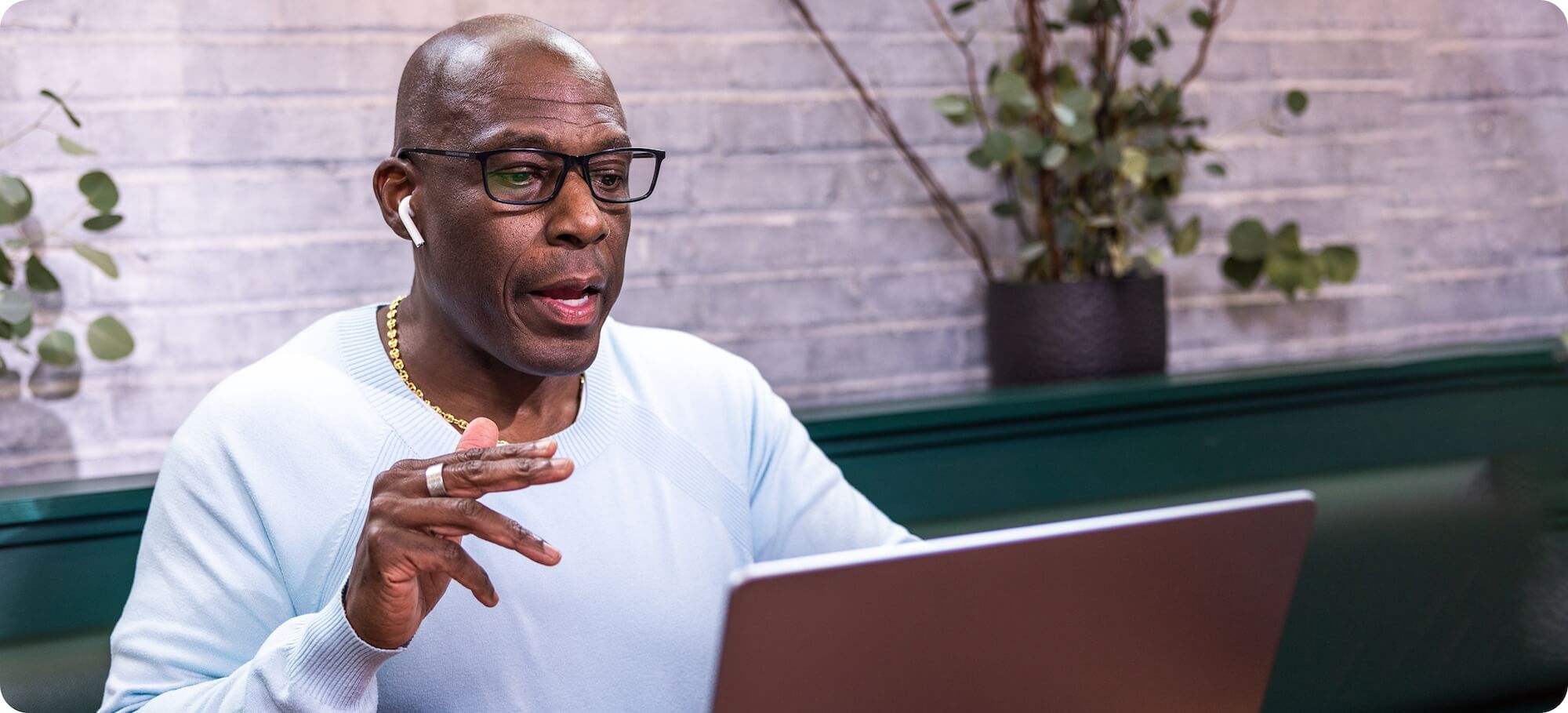 A man wearing earbuds having a meeting on his laptop