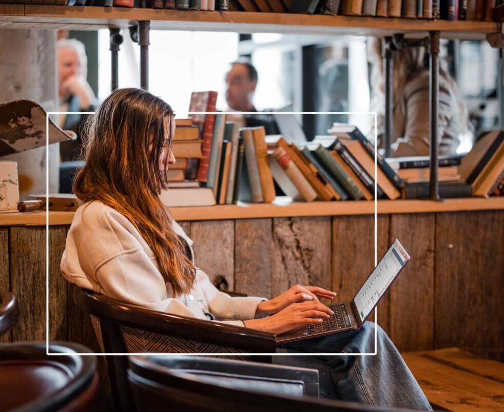 An employee in a cafe working within the Ninety app using her laptop.