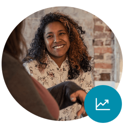 A woman speaking to her colleague and smiling. There is a line chart icon with the line going up in the corner.
