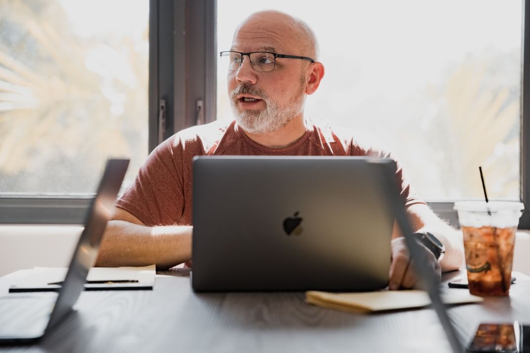 Kris Snyder of Ninety, a Professional EOS Implementer and presenter at EOSCON, working on his laptop and speaking during a meeting.
