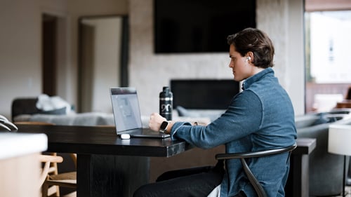A man sits at a desk and types on a laptop.