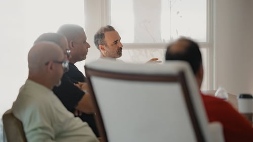 Several men sit around a conference room table.