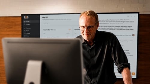 A man stands in front of a large screen.
