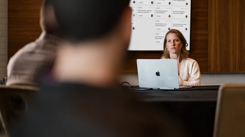 A woman sits at a desk with a computer in front of her. 