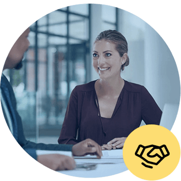 Two people are engaged in a conversation at a table, with one person smiling. A handshake icon is overlaid on the image.