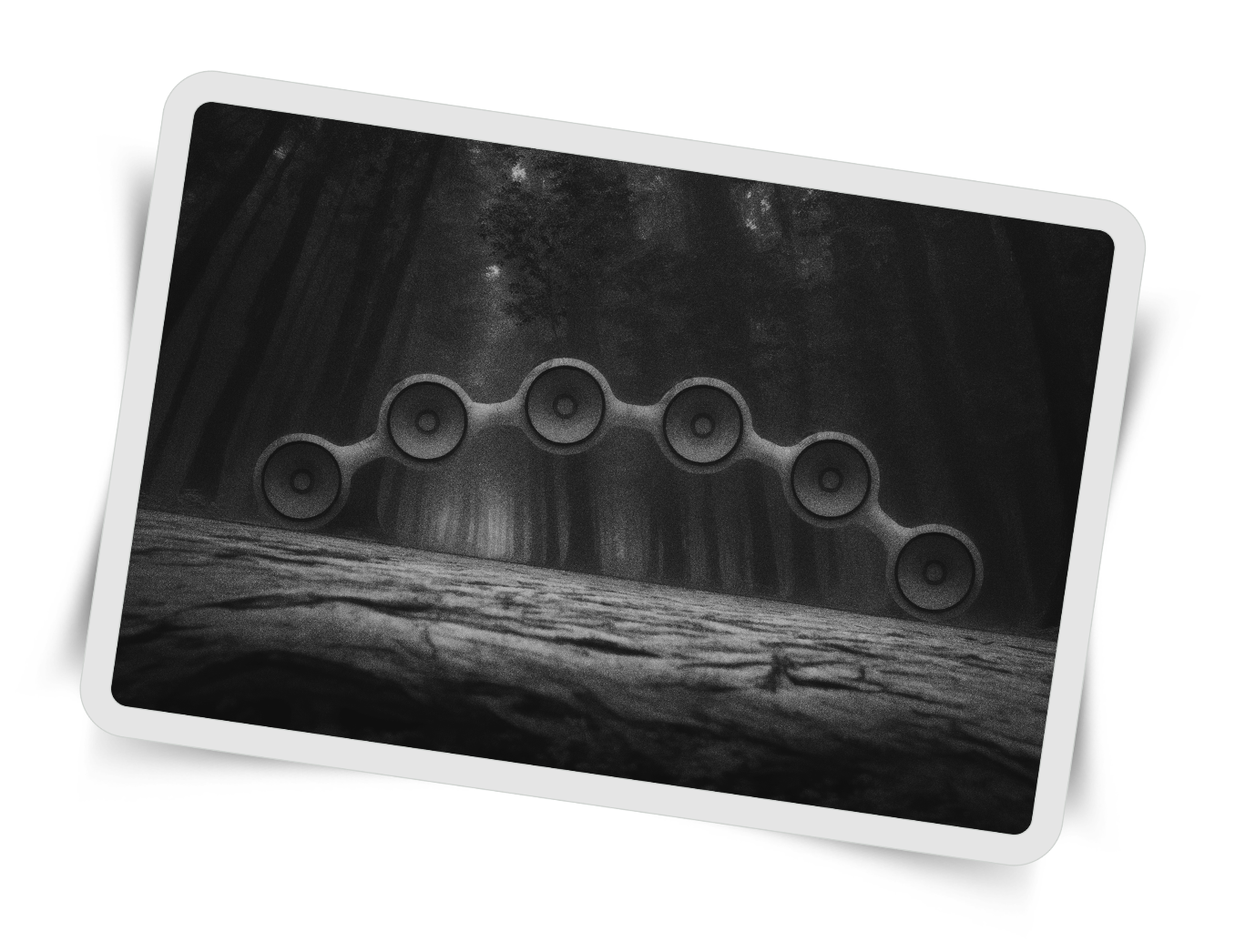A black and white surreal scene depicting a forest with tall, misty trees. At the top, there is a horizontal chain of six circular, speaker-like objects connected by curved lines, suspended in the air between two large tree trunks on either side.