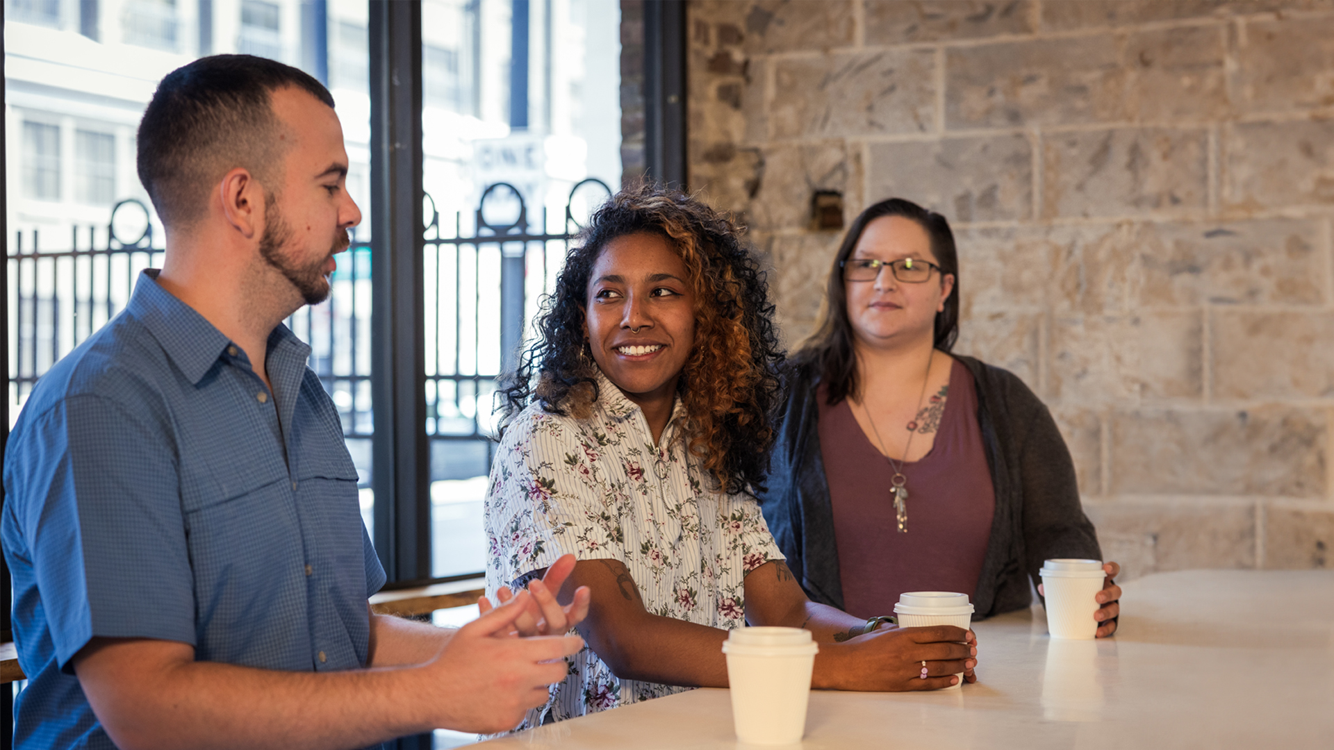 Three Ninety team members are having a discussion at a coffee shop.