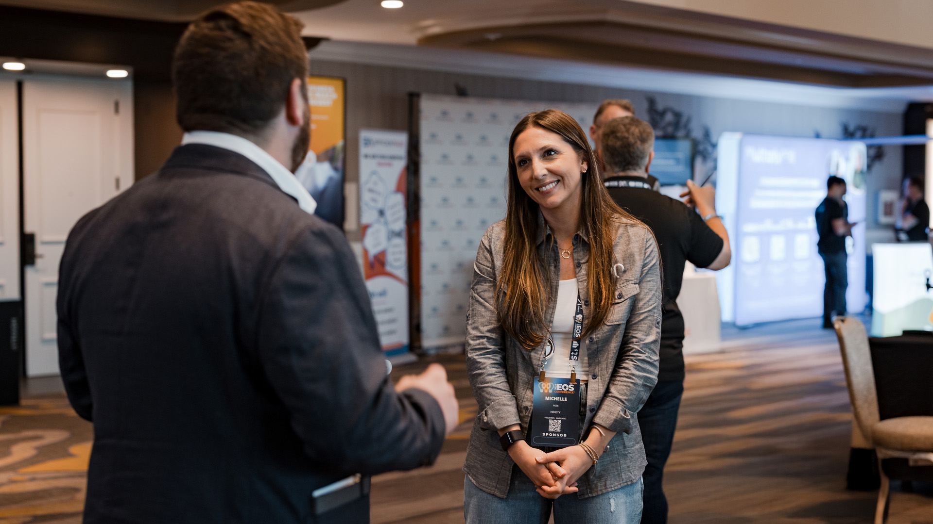 Woman standing and smiling mid conversation at an industry event. 