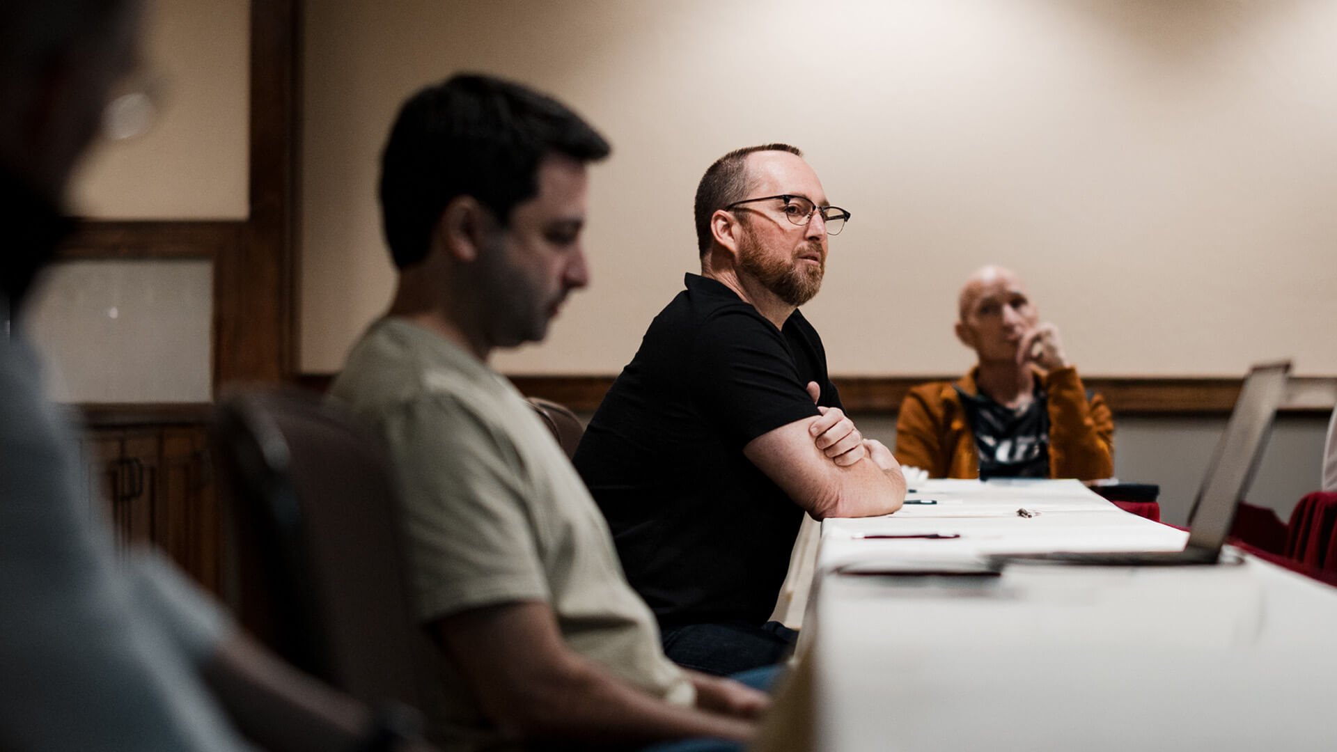 Three men sit at a table.
