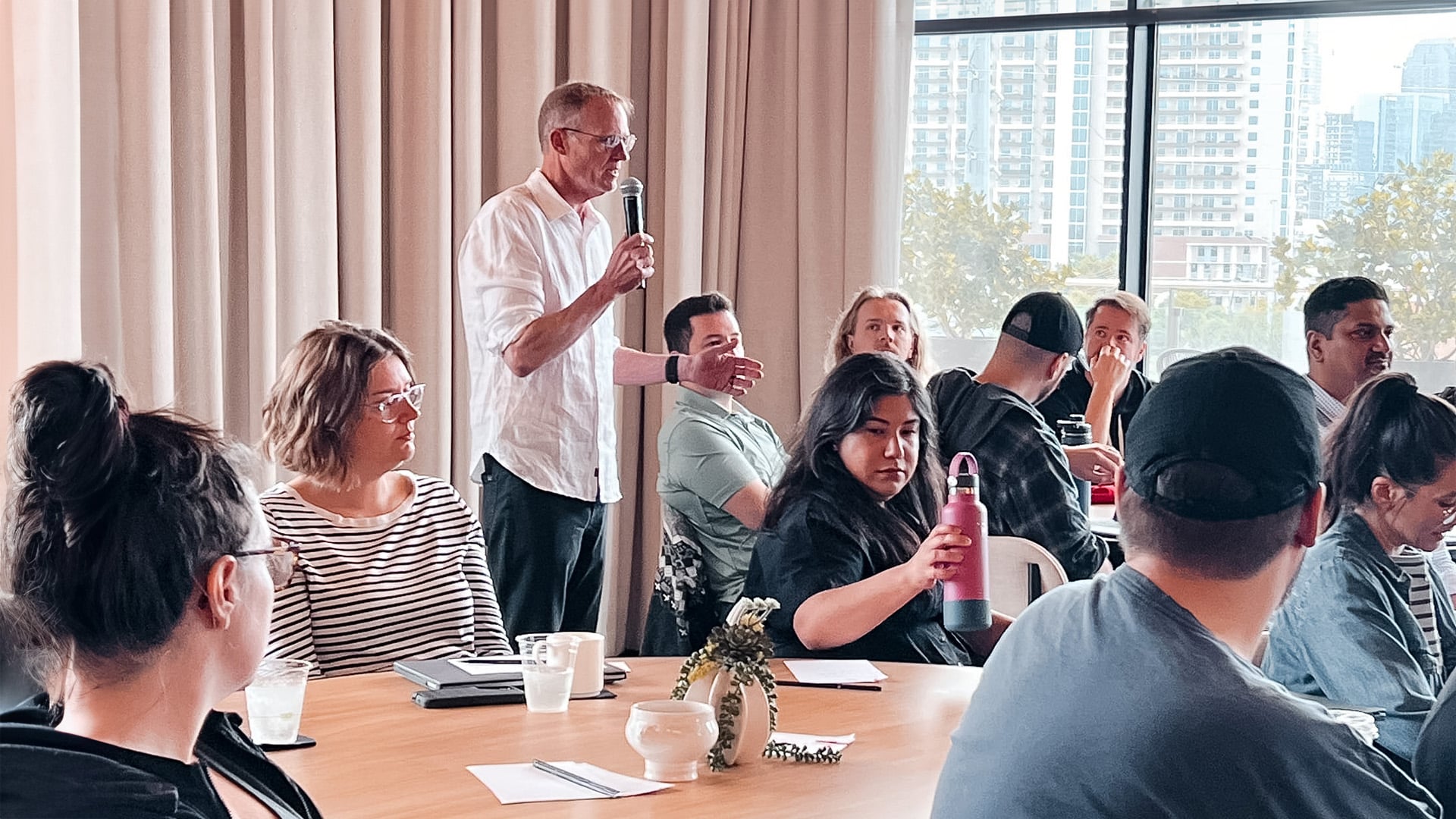 A man talking on a mic to a room full of people.