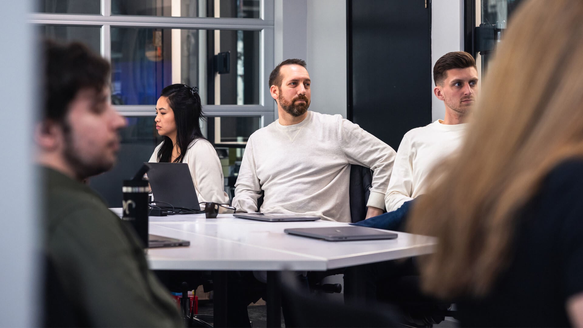 Several people sit at a table in a conference room