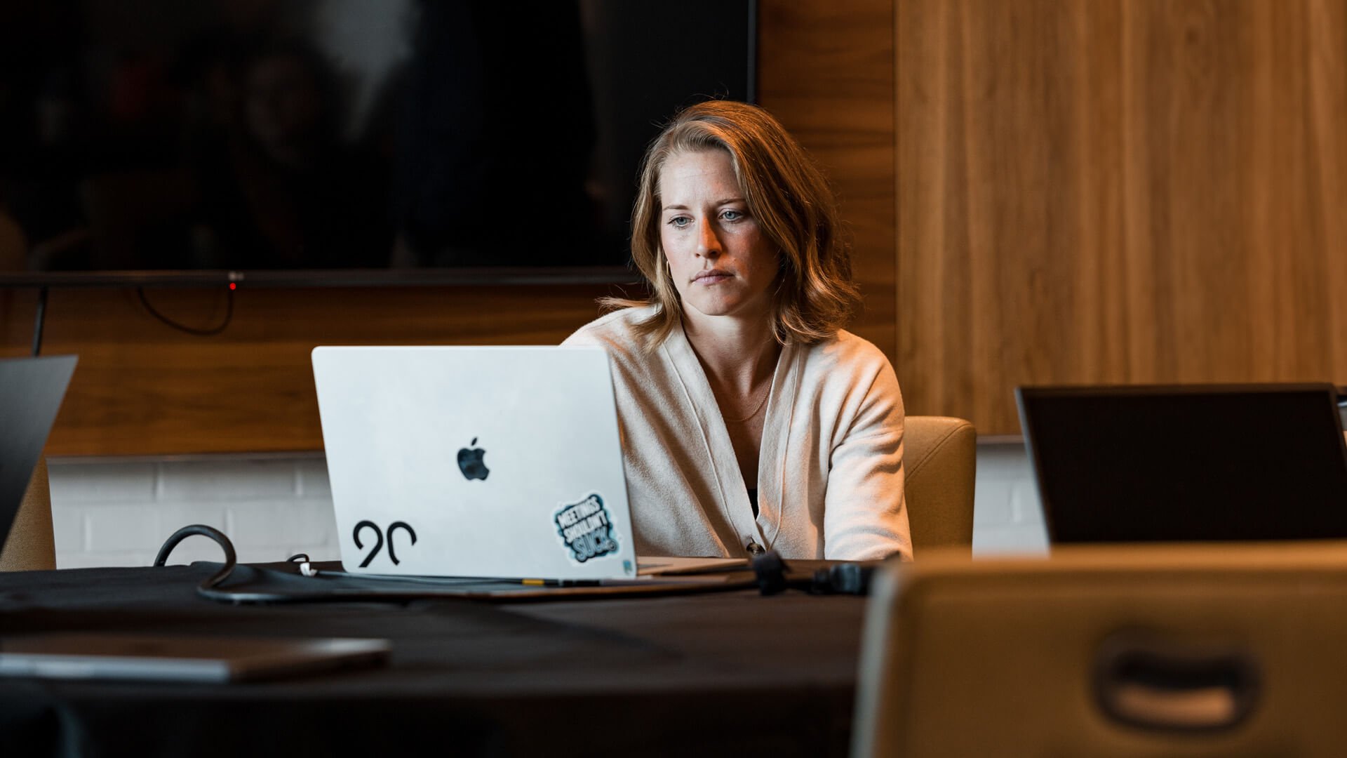 A woman sits at a table and looks at her computer.