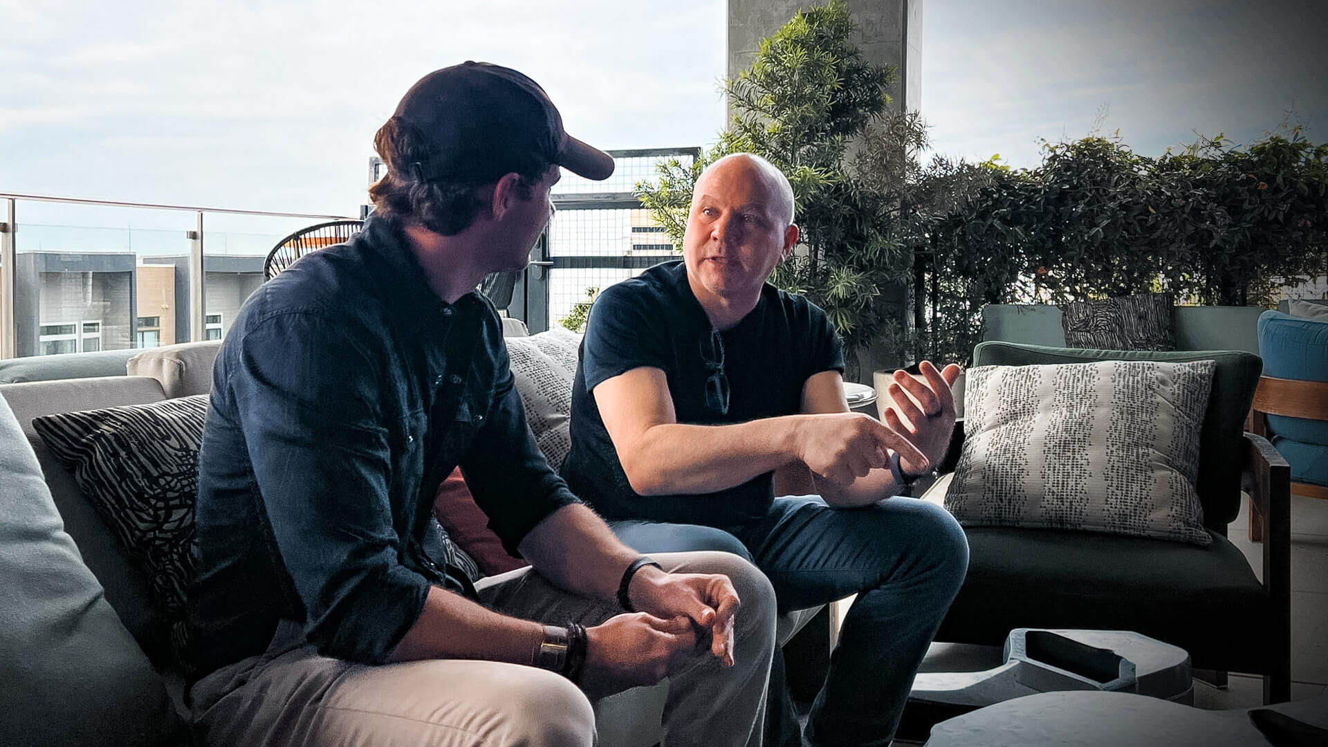 Two men sitting on a patio talking.